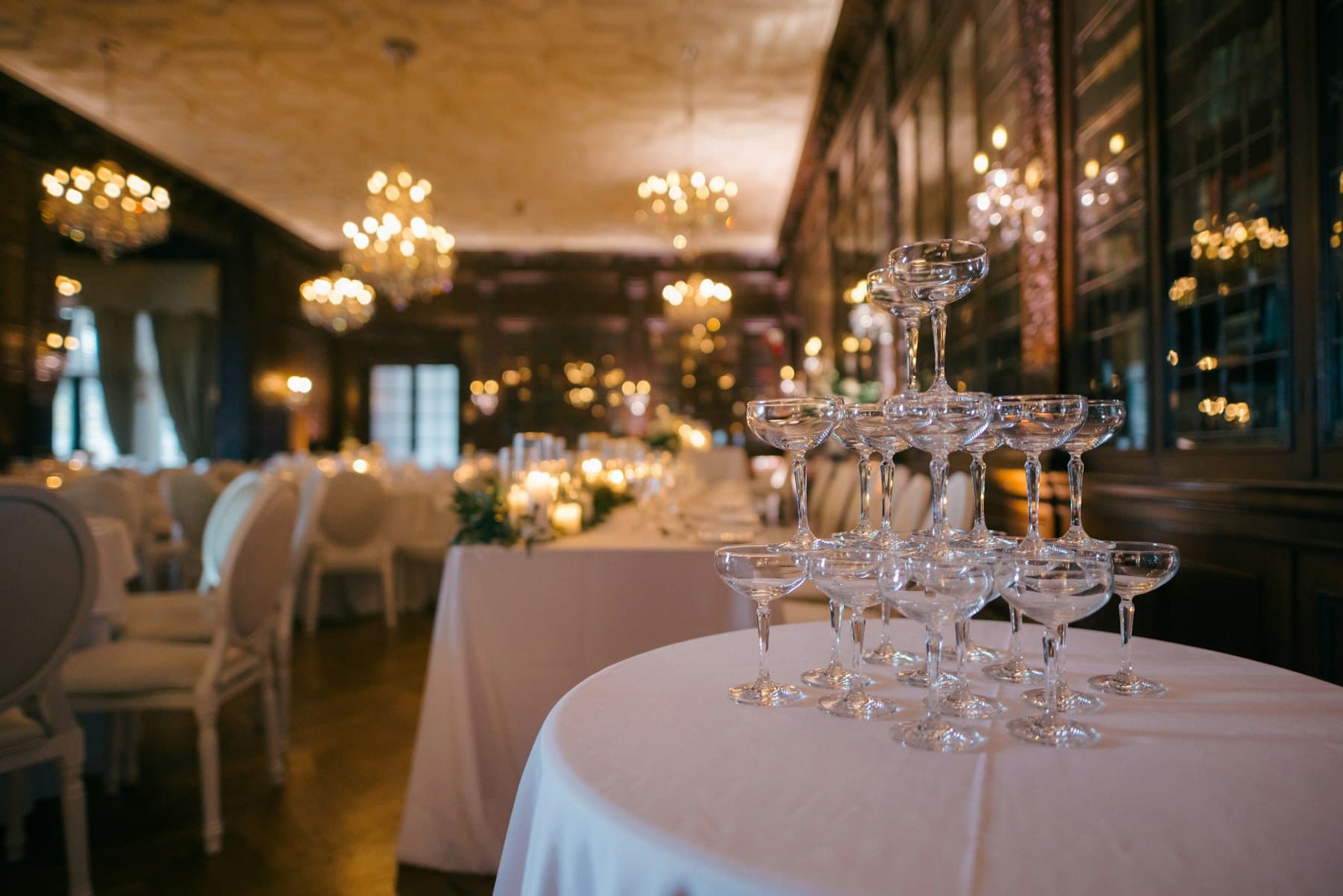 A champagne coupe tower in a candlelit, chandeliered event room