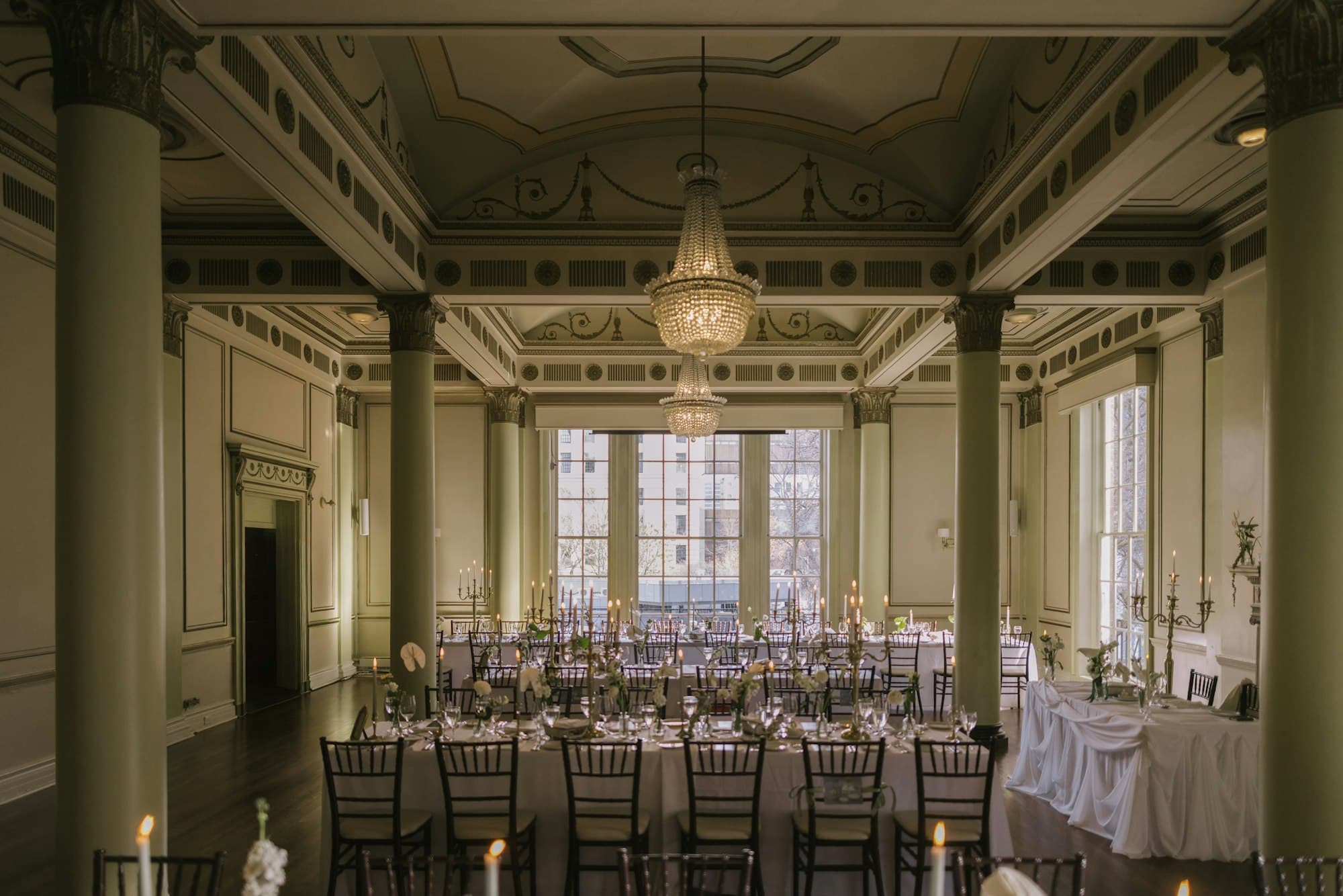 A grand columned ballroom set with candlelit tables